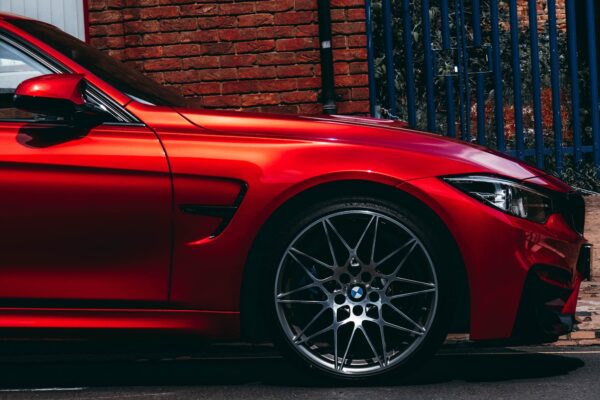 red BMW vehicle parked at the road near the blue gate